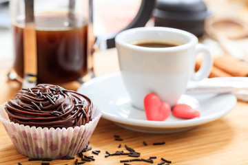 Cup of coffee and a cup cake on a wooden surface
