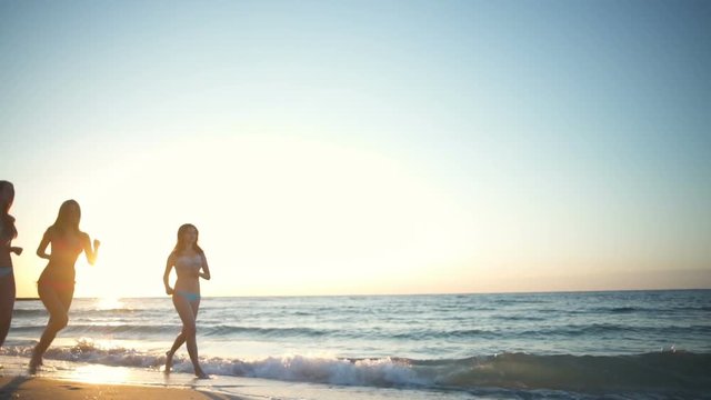 beautiful girls wearing bikini run along the sea slow motion