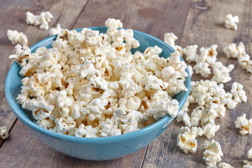 Blue bowl with popcorn on wooden background