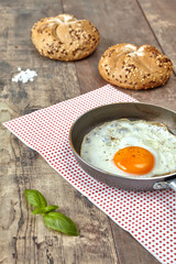 Fried egg in a pan with full grain rolls..