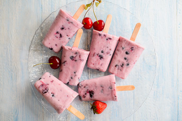 Homemade frozen ice cream popsicles from yogurt and blackcurrant on wooden background, top view