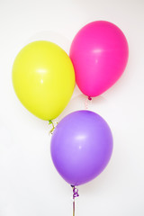 Set of pink, yellow and magenta air balloons against the wall; b