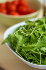 Fresh organic arrugula tossed in a white bowl, unseasoned, with