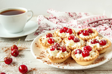 Tartlets with whipped cream and cherry.