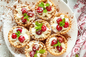 Tartlets with whipped cream and cherry.