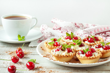 Tartlets with whipped cream and cherry.