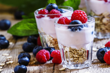 Berry yogurt with muesli, vintage wooden background, selective f