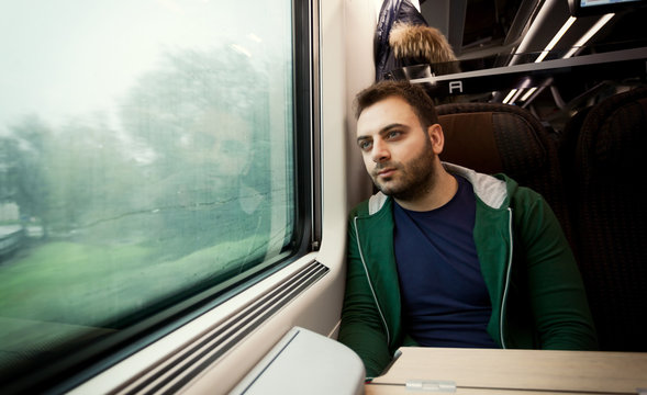Young man staring out the train window.