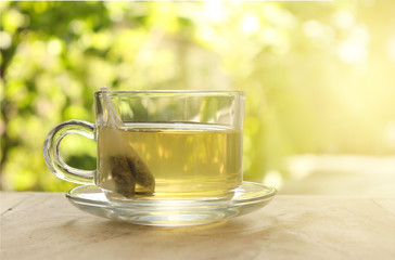 Cup of tea on a blurred background of nature with burst light