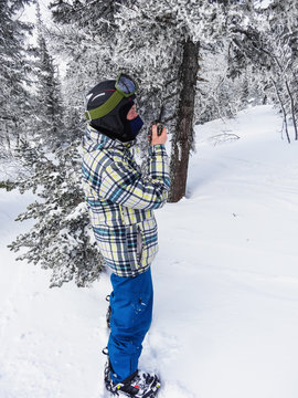 A snowboarder with a walkie-talkie in the woods