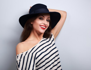 Happy toothy smiling female model in black elegant hat on blue b