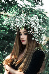 Amazing girl in a black dress and white wreath. Beautiful summer weather. Flowers.