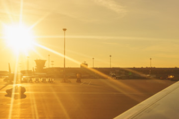 Blurred panorama of an airport with plane and part a terminal at sunrise light.