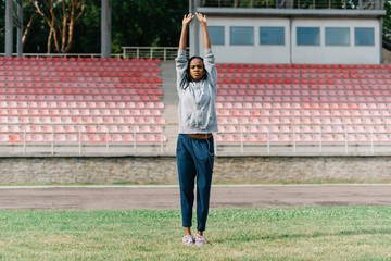 Full length outdoor shot of african young woman on stadium preparing herself for a run