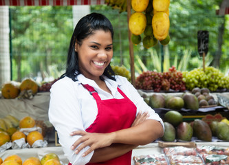 Obraz premium Laughing mexican saleswoman with tropical fruits on farmers market