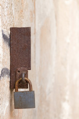 Rusty lock on a rusty metal on a wall