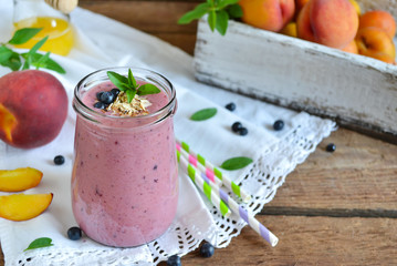 Smoothie of peach, banana and blueberries with oats on a wooden