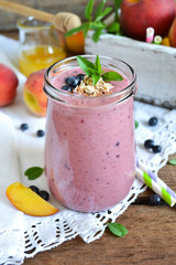 Smoothie of peach, banana and blueberries with oats on a wooden