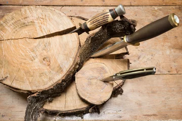 Wandaufkleber Jagdmesser stecken in Stümpfen auf einem Holzhintergrund © stsvirkun