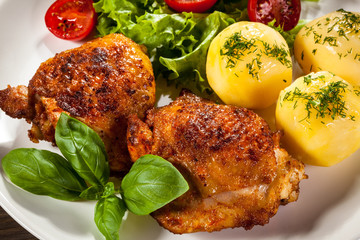 Barbecued chicken legs with boiled potatoes and vegetables