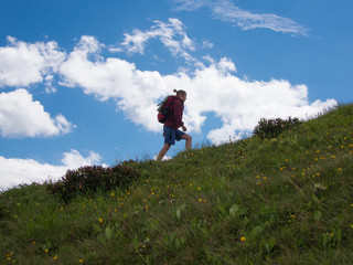 Woman going up the hill on a background of blue sky