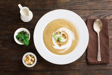 Mushroom cream soup with fried mushrooms and fresh herbs on rustic white wooden table, top view