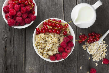 Oatmeal with raspberry and red currant on a wooden background