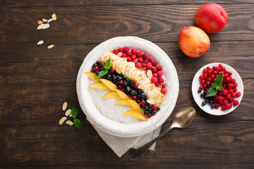 Homemade rice pudding with fresh fruits, wooden background, top view