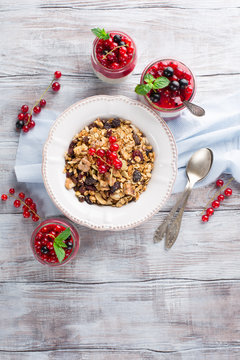 Healthy breakfast with yogurt, homemade granola and fresh berries, top view. White wooden background