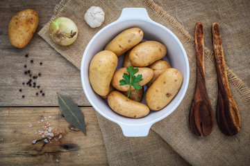 Fresh organic potatoes in white ceramic bowl with ingredients an