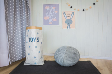 Two nice pictures, bag for toys and bear on the pouf in children's bedroom