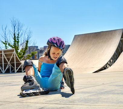 Child riding on roller skates in skatepark. Child roller fall down in roller skates.