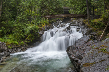 Deception Falls, Skykomish, Washington.  Deception Creek crashes down a few steps, then glides over smooth rock under the highway and ends in a square, misty plunge before emptying into the Tye River.