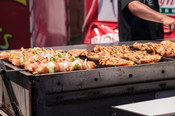 Chicken, beef and onion kabobs on a barbecue grill cooking at a fair ground.