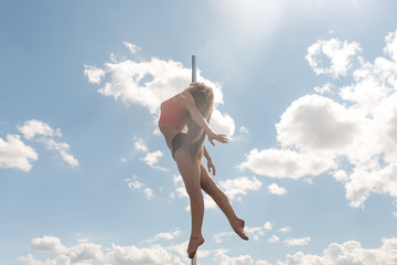 Pole dance fit woman exercising with pylon outdoors
