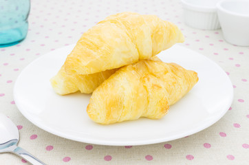 Croissant or Bakery on White Dish on Placemat with Glass and Spoon