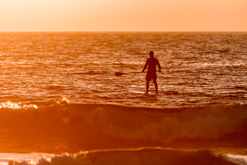 Fototapeta na wymiar Stand up paddler silhouette at sunset