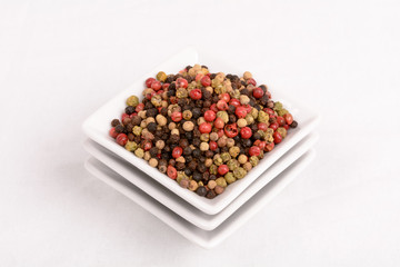 Grains of colored pepper produce fragrant. / Colorful peppercorns in a white mixing bowl. Horizontal cut with white background.