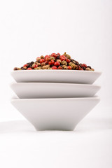 Grains of colored pepper produce fragrant. / Colorful peppercorns in a white mixing bowl. Horizontal cut with white background.