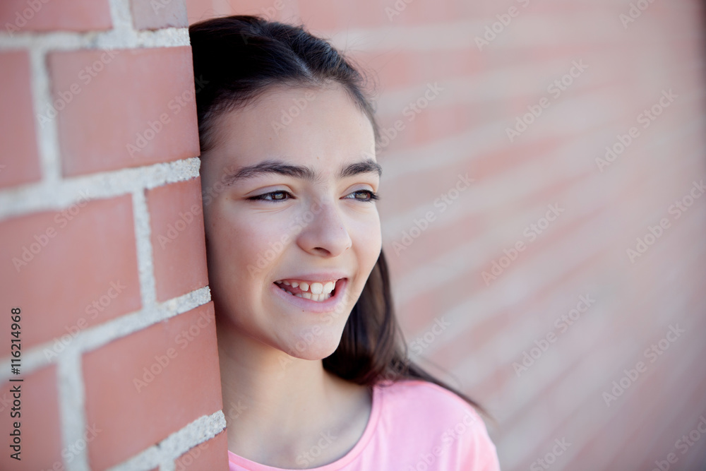 Wall mural Preteenager girl next to a red brick wall