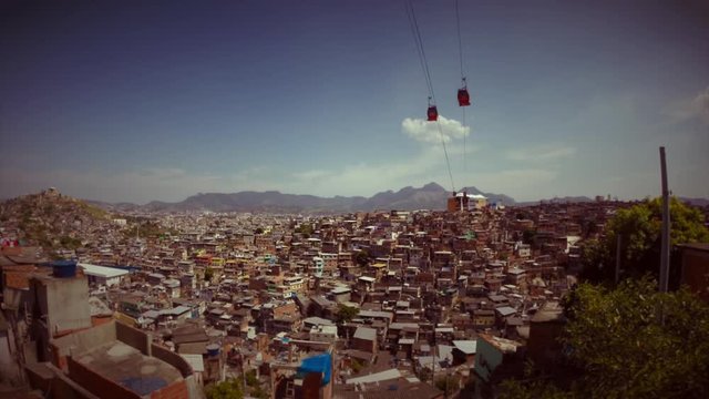 Cable cars travel across a hillside skyline filled with breezeblock houses of the Complexo Alemao favela in Rio de Janeiro, Brazil