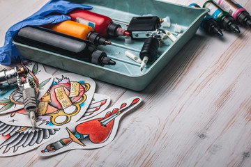 Replacement supplies for tattoo in sterile packages, sketches, inks and a tattoo machine on the...