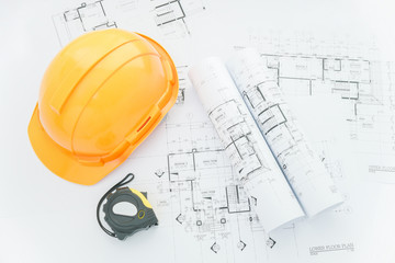 architects workplace - architectural blueprints with measuring tape, safety helmet and tools on table. top view 