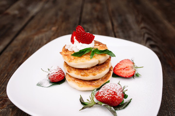 Pancakes pile with strawberry on wooden background. Rustic homemade dessert with flapjack and fresh berries