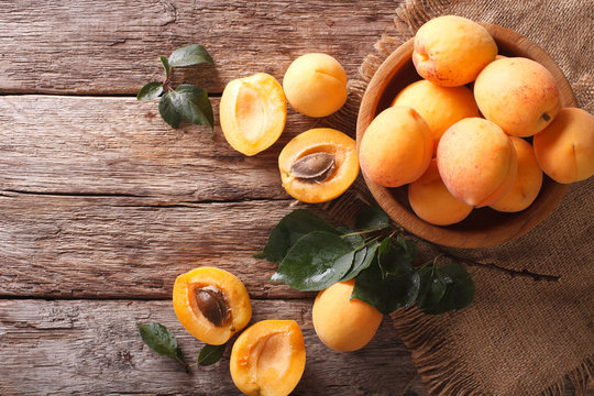 ripe apricots in a wooden bowl on the table closeup. horizontal top view

