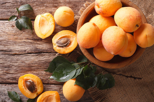 Fresh apricots in a wooden bowl on the table close-up. horizontal top view
