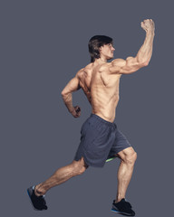 Shirtless muscular male in action isolated on a grey background.