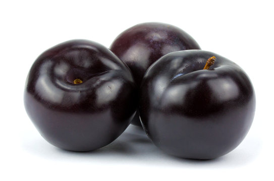 three black plums, isolated on white background