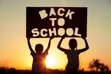 Happy children playing on the field at the sunset time.