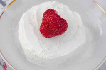 Red strawberry on white icecream in plate. Dessert macro view.